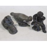 A collection of four soapstone Inuit carvings, including two seals and two hunters. Markings on
