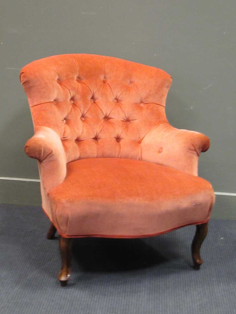 An early Victorian peach upholstered button back armchair the outswept arms on cabriole legs