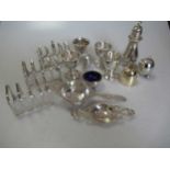 A collection of silverware including 3 toastracks, 4 egg cups, 2 tea strainers, a pepper caster, a
