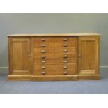 A 20th century blonde oak breakfront plan/ map chest, comprising of seven long drawers flanked by