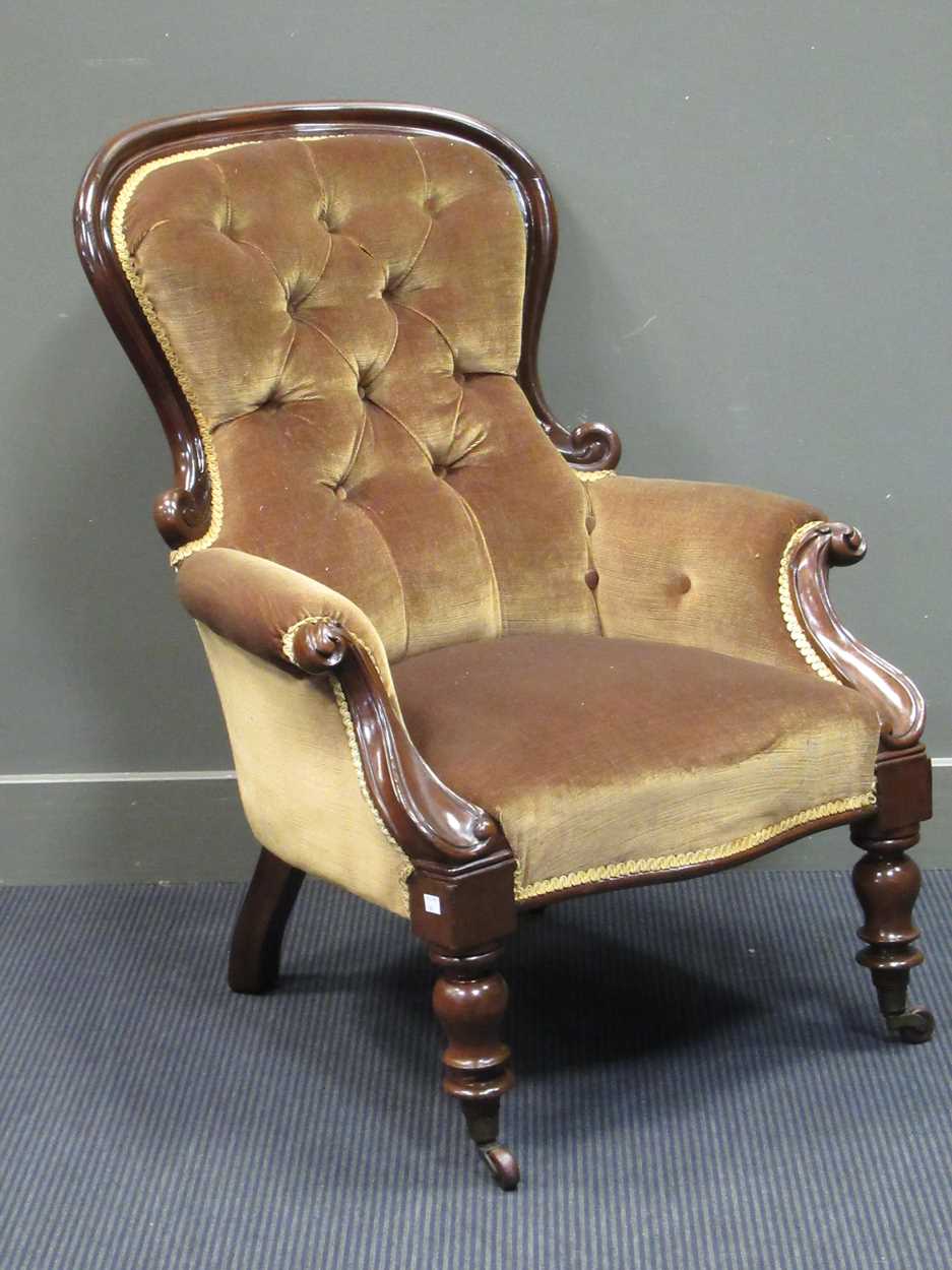 A mid-Victorian mahogany button back scroll carved armchair on turned legs and ceramic castors