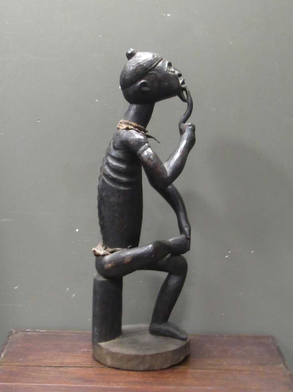 A 20th century African carved figure of seated male smoking a pipe, mirror insert to the side of the - Image 8 of 9