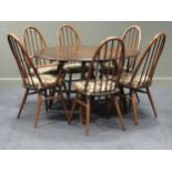 An Ercol Model 377 dark stained beech and elm drop leaf dining table and six (4 + 2) chairs