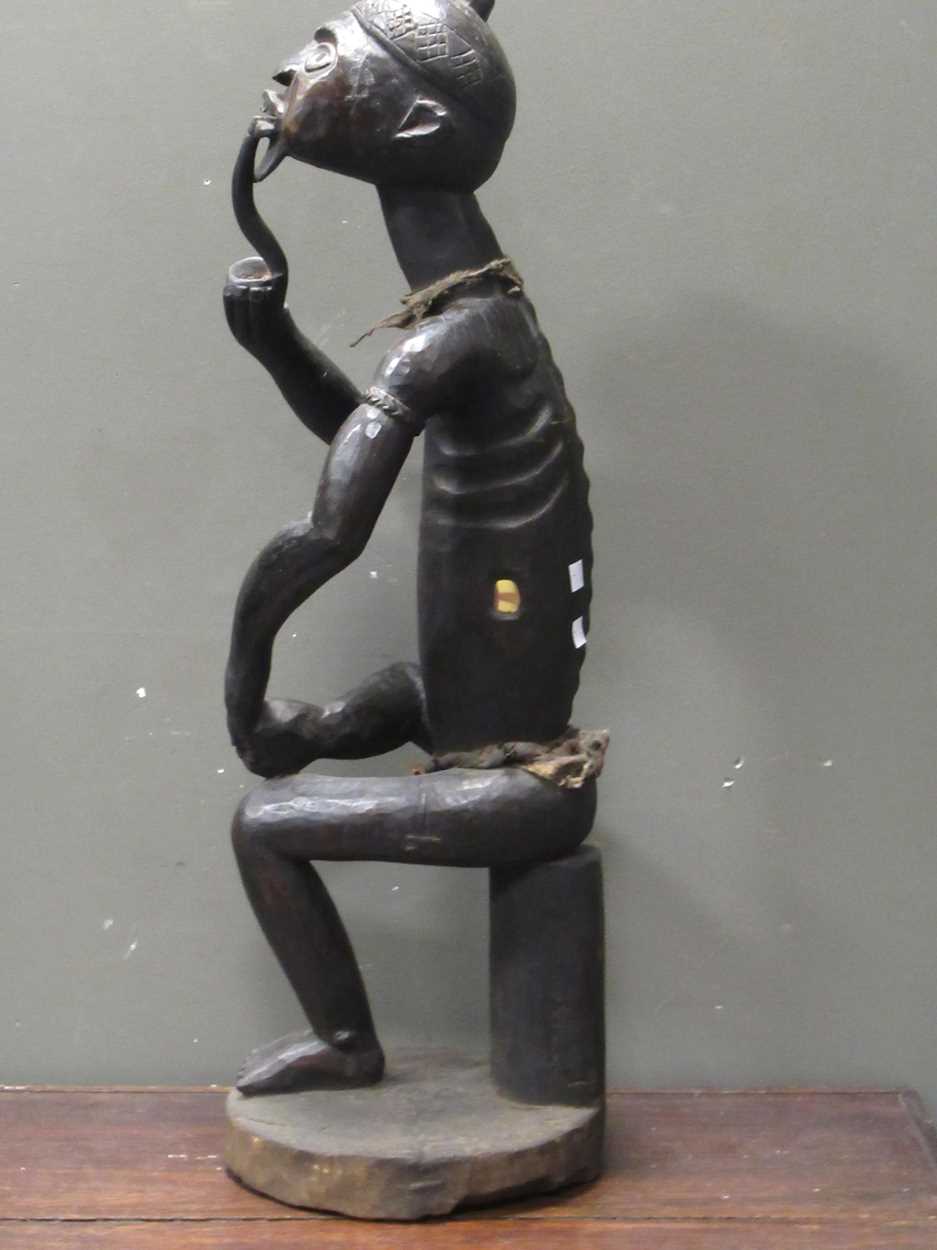 A 20th century African carved figure of seated male smoking a pipe, mirror insert to the side of the - Image 6 of 9