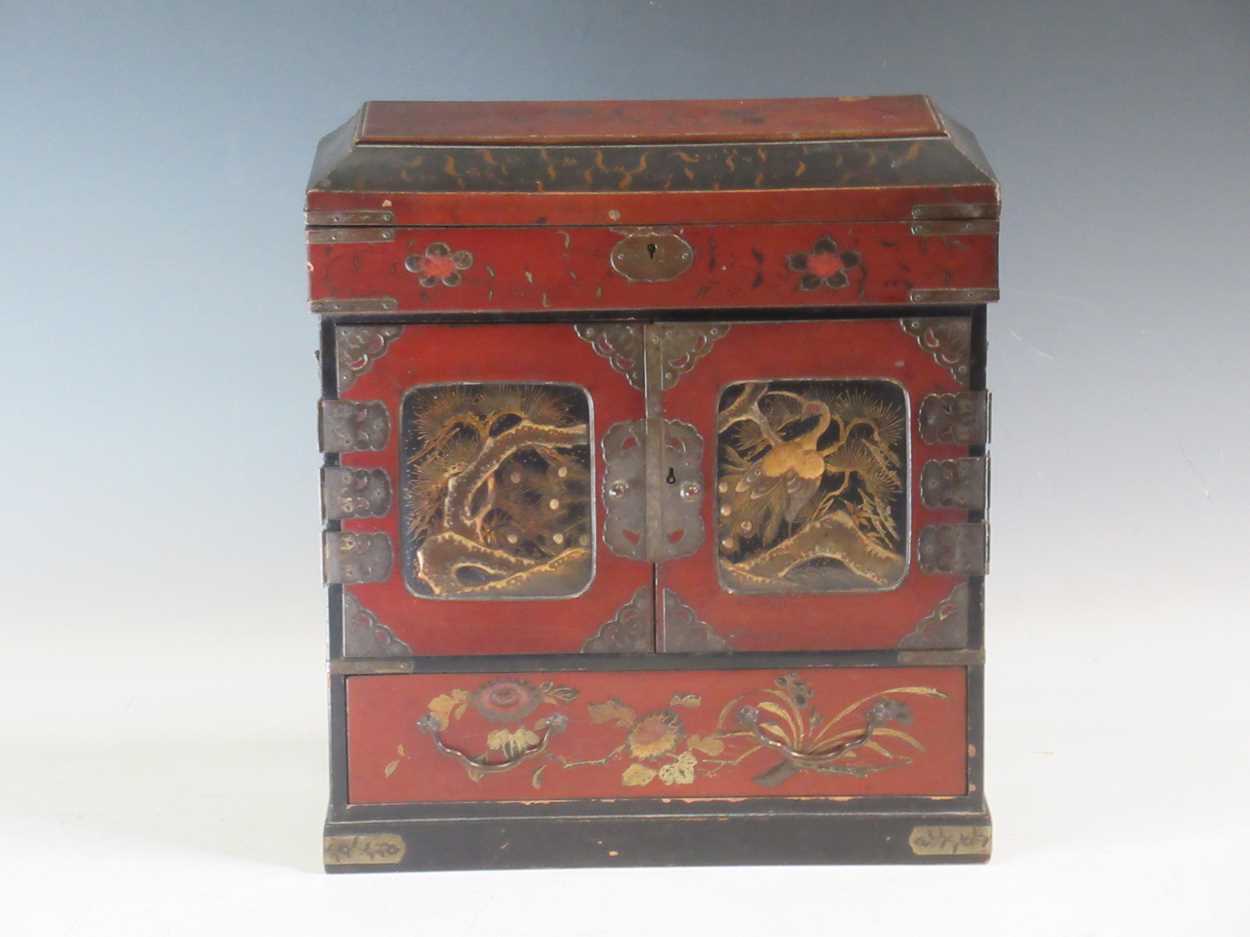 A Japanese meiji period lacquered table cabinet, the two doors enlcosing drawers, with side