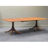 A George III reproduction mahogany twin pedestal dining table, on fluted out swept legs capped