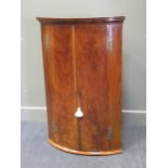 A 19th century bow fronted corner cupboard with H shaped hinges and key 111cm high, 72.5cm wide 50cm