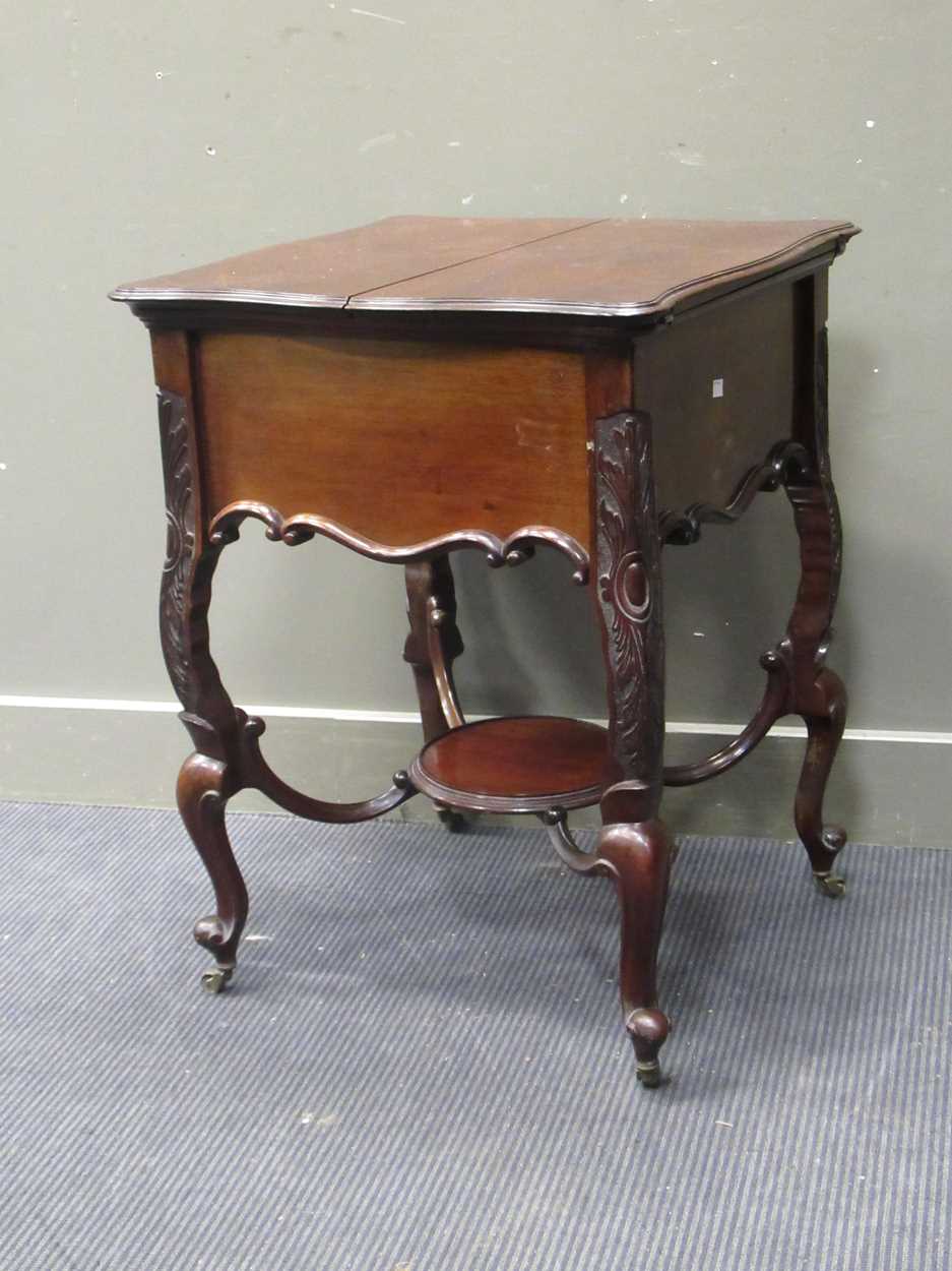 An Edwardian mahogany drinks table, the folding top opening to reveal a pop-up drinks tray, 78 x