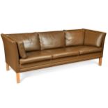 A modern brown leather three-seat sofa, with loose cushions and raised on square section legs70 x
