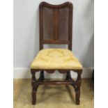 A 17th century oak and cane chair with a yellow upholstered seat