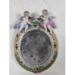 A continental porcelain mirror, mounted with two cherubs 24cm high