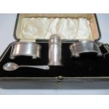 A cased silver three-piece condiment set, all with blue glass liners - one spoon lacking