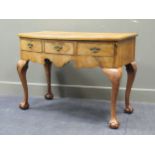 A walnut bow front dressing table with glass top, comprising of three drawers raised on shell carved