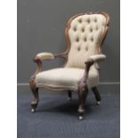 A late Victorian walnut button back arm chair on cabriole legs