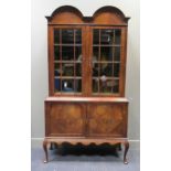 An Edwardian walnut double dome top glazed panel two door bookcase on base over cabriole legs with