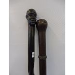 An African hardwood walking cane, the knop carved as a man's head, and a second walking cane.