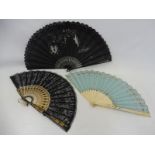 Three decorative fans including one with lace embellishments and cherubs.