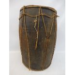 An early, possibly tribal, wooden and rope bound drum with vellum top and bottom, and metal patch