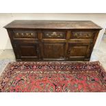 An 18th Century oak dresser base of three frieze drawers above two cupboards and central panel,