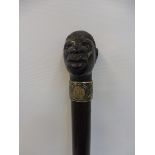 A hardwood walking cane with an Art Nouveau silver collar surmounted by an ebony knop in the form of
