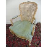 A limed wood cane back armchair with a loose cushion.