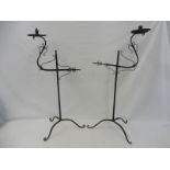 A pair of Arts and Crafts wrought iron floor standing adjustable candle sticks with circular drip