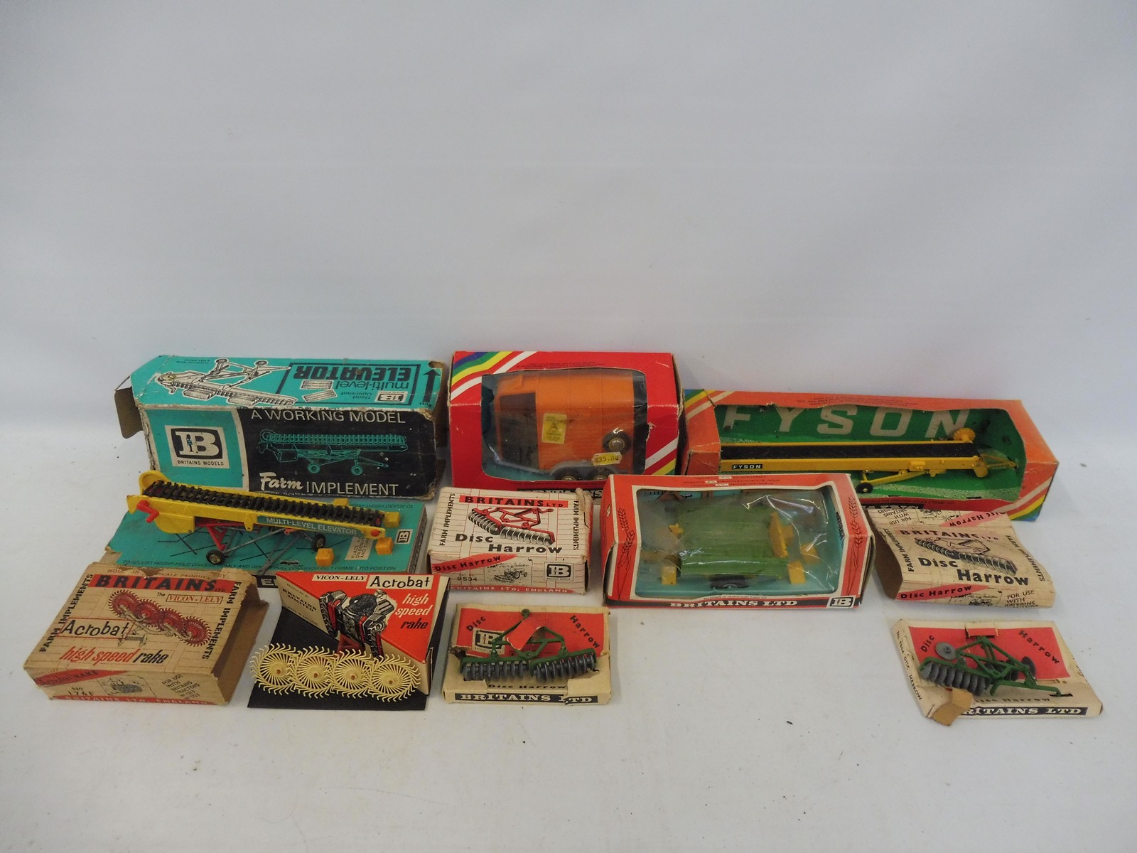 An assortment of Britains farm accessories from different eras, boxes in various conditions.