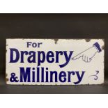 A 'For Drapery & Millinery' enamel sign with pointing hand image to one corner, 36 x 17".