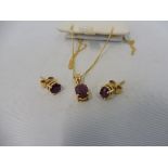 An 18ct yellow gold and ruby pair of earrings with matching pendant. .