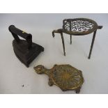 A heavy flat iron marked Silvesters Patent and a trivet marked R M M. plus two brass trivets.