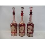 Three matching 19th Century bohemian ruby flash cut decanters and stoppers.