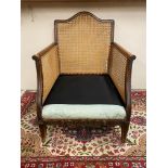 An Edwardian begere armchair lacking cushion.