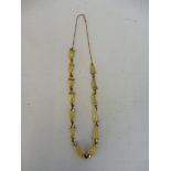 A yellow metal mounted reptile tooth necklace.