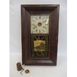 An early 20th Century American style wall clock with a decorative glass panel below the dial.