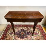 A 19th Century mahogany fold over card table with green baize interior raised upon ring turned