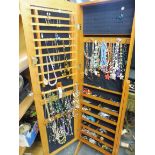 A floor standing jewellery cabinet containing a large quantity of costume jewellery .