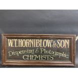 A contemporary and decorative painted wooden sign advertising W.T.Horniblow & Son Dispensing &