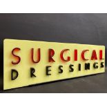 A chemist's show window perspex advertising sign for 'Surgical Dressings', 20 x 6 1/4".