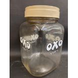 An OXO cubes glass counter top jar with cream and red lettered screw on plastic lid.
