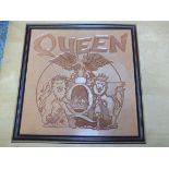 A commissioned Queen embossed leather logo, framed.