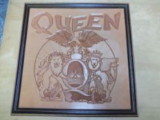 A commissioned Queen embossed leather logo, framed.