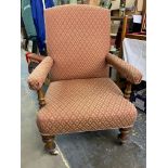 A Victorian upholstered armchair, raised upon turned front supports, to castors.