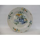 An 18th Century Delft charger, the design with brightly coloured flowers, 12" diameter.