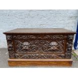 An unusual oak low chest with a deep single drawer, heavily carved with two grotesque faces, 44" w x