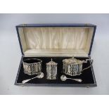 A cased silver condiment set of large impressive form, with part pierced design and blue glass