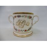 A large 19th Century two handled loving mug, decorated with a garland of flowers and gilded initials