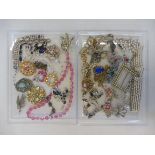 Two trays of highly decorative kitch jewellery, comprising brooches, bracelets, necklaces etc.