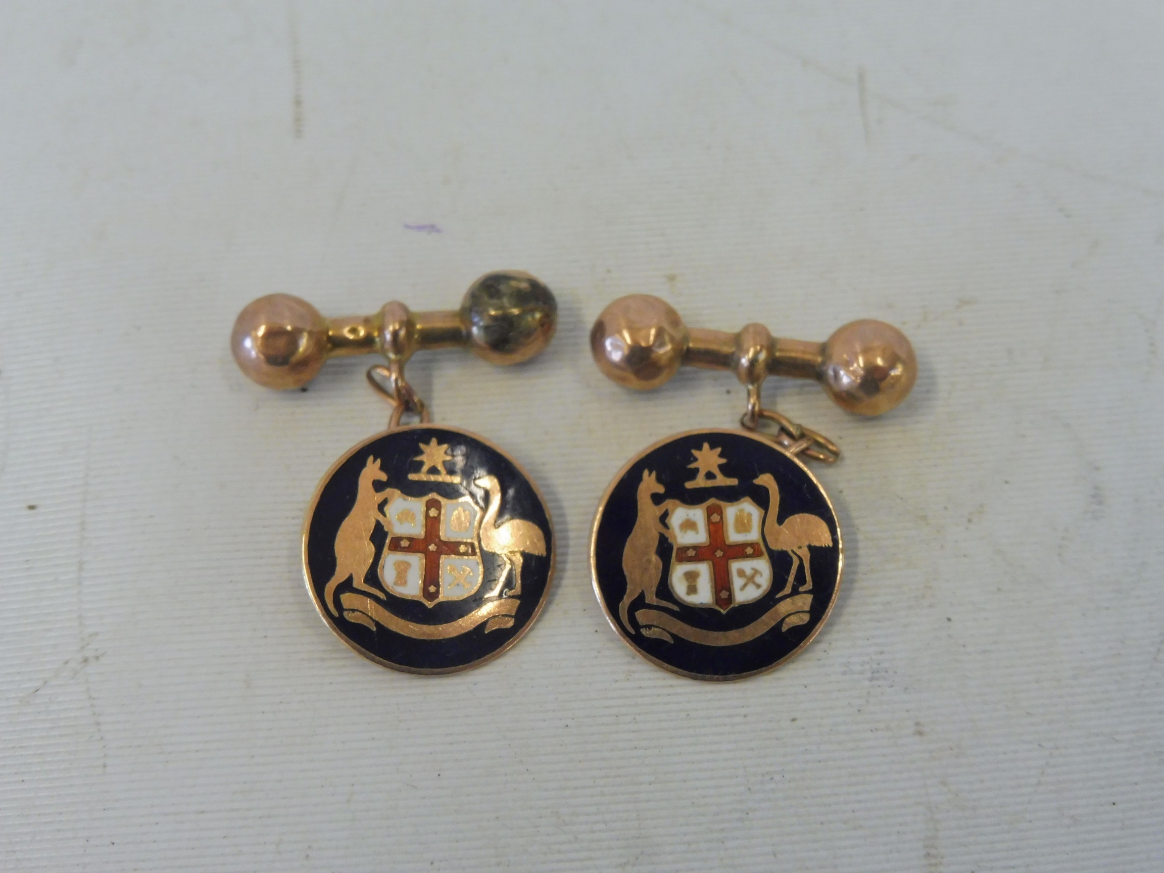 A pair of 9ct gold and enamel cufflinks, with a coat of arms flanked by a kangaroo and an emu or