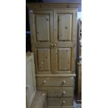 A vintage pine Tallboy, the two doors enclosing a shelved interior with a clothing rail, raised on