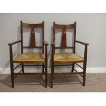 A pair of Arts and Crafts oak Carver Chairs, with rush seats, splat back with carved heart motif,